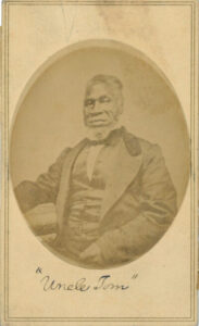 A historical sepia toned image of an older African American man with a white beard and a dressy suit. Nineteenth century.